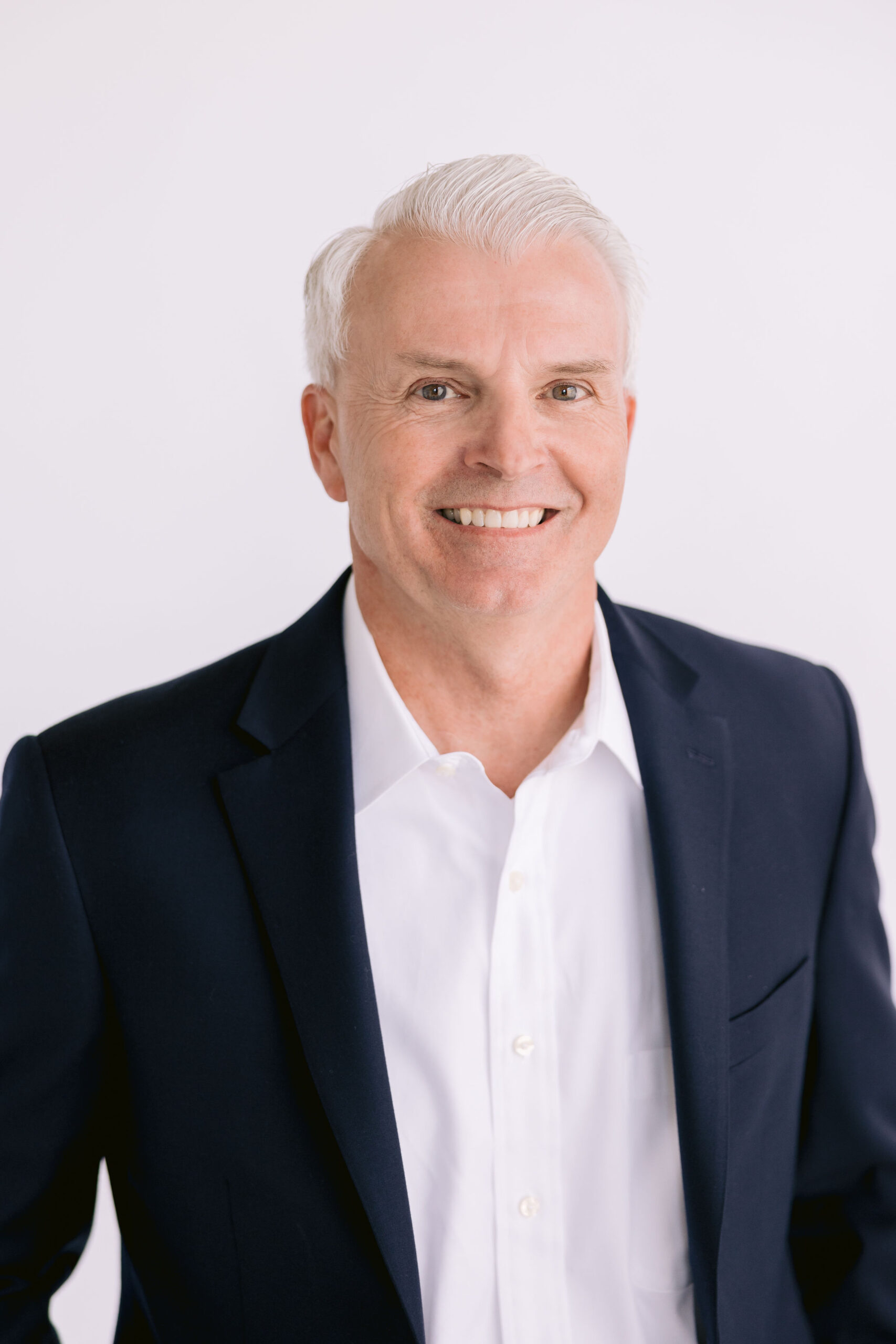 Doug Bergman Man in black jacket and white collared button down shirt smiling.